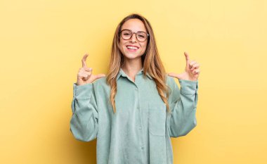 pretty caucasian woman framing or outlining own smile with both hands, looking positive and happy, wellness concept
