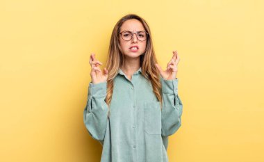pretty caucasian woman crossing fingers anxiously and hoping for good luck with a worried look