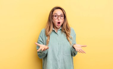 pretty caucasian woman open-mouthed and amazed, shocked and astonished with an unbelievable surprise
