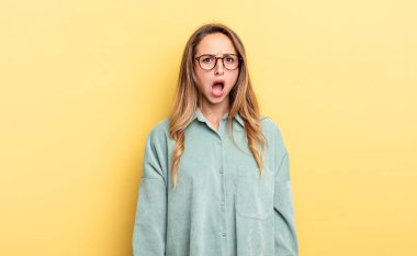 pretty caucasian woman feeling terrified and shocked, with mouth wide open in surprise