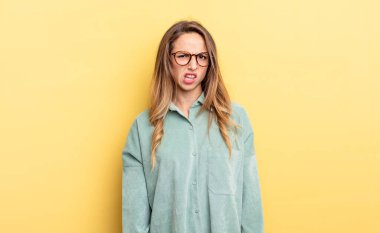pretty caucasian woman feeling puzzled and confused, with a dumb, stunned expression looking at something unexpected