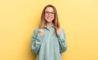 pretty caucasian woman shouting triumphantly, laughing and feeling happy and excited while celebrating success