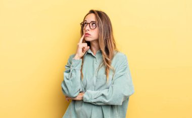 pretty caucasian woman with a concentrated look, wondering with a doubtful expression, looking up and to the side