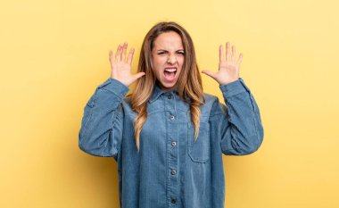 pretty caucasian woman screaming in panic or anger, shocked, terrified or furious, with hands next to head
