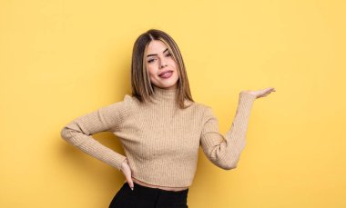 pretty caucasian woman smiling, feeling confident, successful and happy, showing concept or idea on copy space on the side