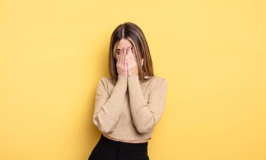 pretty caucasian woman feeling sad, frustrated, nervous and depressed, covering face with both hands, crying