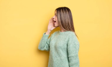 pretty caucasian woman profile view, looking happy and excited, shouting and calling to copy space on the side