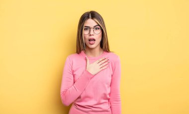 Güzel, beyaz bir kadın şok olmuş ve şaşırmış hissediyor, gülümsüyor, el ele tutuşuyor, mutlu ya da şükran duyuyor.