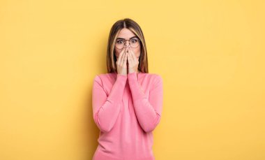 pretty caucasian woman feeling worried, upset and scared, covering mouth with hands, looking anxious and having messed up
