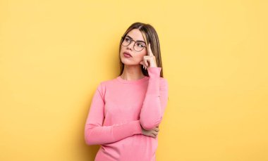 pretty caucasian woman with a concentrated look, wondering with a doubtful expression, looking up and to the side