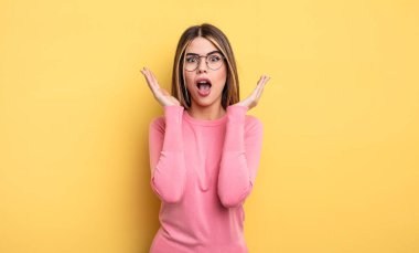 pretty caucasian woman feeling shocked and excited, laughing, amazed and happy because of an unexpected surprise