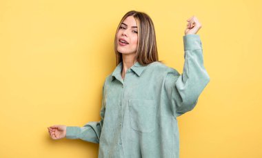 pretty caucasian woman smiling, feeling carefree, relaxed and happy, dancing and listening to music, having fun at a party