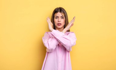 pretty caucasian woman looking annoyed and sick of your attitude, saying enough! hands crossed up front, telling you to stop