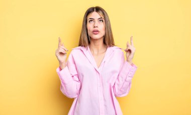 pretty caucasian woman feeling awed and open mouthed pointing upwards with a shocked and surprised look