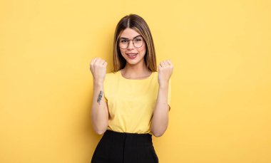 pretty caucasian woman shouting triumphantly, laughing and feeling happy and excited while celebrating success