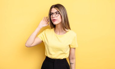 Oldukça beyaz bir kadın ciddi ve meraklı görünüyor, dinliyor, gizli bir konuşma veya dedikodu duymaya çalışıyor, kulak misafiri oluyor.