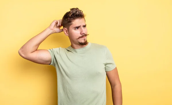 Jovem Homem Bonito Sentindo Perplexo Confuso Coçando Cabeça Olhando Para — Fotografia de Stock