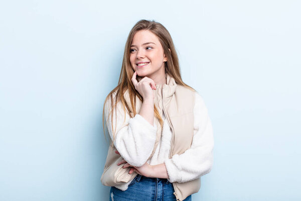 кавказская рыжая женщина улыбается счастливо и мечтает или сомневается, смотрит в сторону