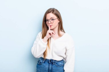 Kafkasyalı kızıl saçlı kadın sessizlik ve sessizlik istiyor, parmağıyla ağzının önünde işaret ediyor, 