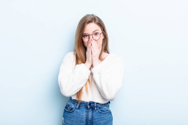 Kafkasyalı kızıl saçlı kadın mutlu ve heyecanlı, şaşırmış ve şaşırmış elleri ile ağzını kapatmış, tatlı bir ifadeyle kıkırdıyor.