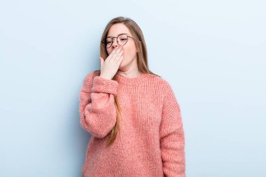 Kafkasyalı kızıl saçlı kadın sabahın erken saatlerinde uyanıyor ve uykulu, yorgun ve sıkılmış görünüyor.