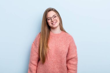 Kafkasyalı kızıl saçlı kadın neşeli, mutlu, kendinden emin ve rahat bir ifadeyle gülümsüyor.