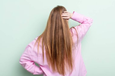 Kafkasyalı kızıl saçlı kadın düşünüyor ya da şüphe ediyor, kafasını kaşıyor, kafası karışık ve kafası karışık, geriye ya da arkaya bakıyor.