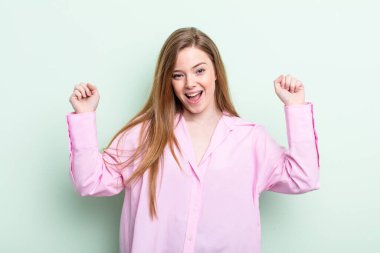 Kafkasyalı kızıl saçlı kadın son derece mutlu ve şaşırmış görünüyor, başarıyı kutluyor, bağırıyor ve zıplıyor.