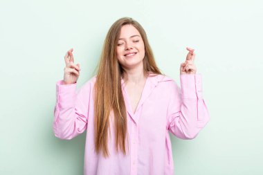 Kafkasyalı kızıl saçlı kadın gülümsüyor ve endişeyle iki parmağını çapraz yapıyor. Endişeli ve iyi şanslar diliyor.