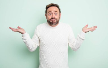 Orta yaşlı yakışıklı adam şaşkın ve şaşkın, şüpheci, ağırlıklı ya da farklı seçenekleri komik bir ifadeyle seçiyor.