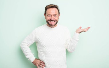 Orta yaşlı yakışıklı adam gülümsüyor, kendinden emin, başarılı ve mutlu hissediyor, fotokopi alanında fikir veya konsept gösteriyor.