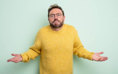 middle age handsome man feeling clueless and confused, having no idea, absolutely puzzled with a dumb or foolish look