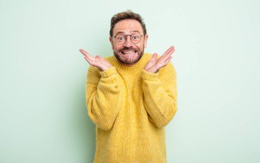 Orta yaşlı yakışıklı adam mutlu ve heyecanlı görünüyor. Beklenmedik bir sürprizle şoke olmuş. İki eli de açık.