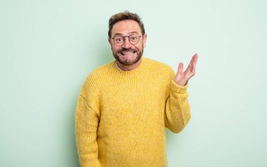 Orta yaşlı yakışıklı bir adam mutlu, şaşkın ve neşeli, olumlu bir tavırla gülümseyen, bir çözüm ya da fikir gerçekleştiren