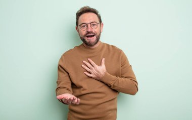 Orta yaşlı yakışıklı bir adam mutlu ve aşık, bir eli kalbinin yanında gülümsüyor ve diğer eli önde uzanıyor.