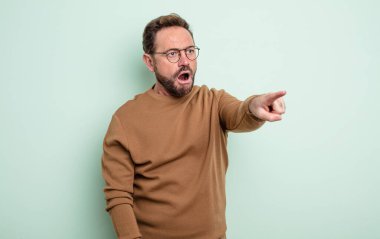 Orta yaşlı yakışıklı bir adam şok olmuş ve şaşırmış hissediyor. Şaşırmış ve ağzı açık bir şekilde hayranlıkla yukarı bakıyor.