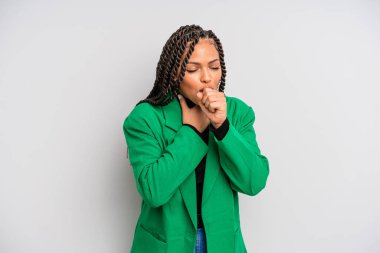 Boğazı ağrıyan ve grip belirtileri gösteren, ağzı kapalı öksüren siyah afro bir kadın.