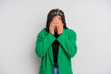 Siyah afro kadın üzgün, hayal kırıklığına uğramış, gergin ve depresif, iki eliyle yüzünü kaplayan, ağlayan