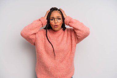 Siyah afro kadın heyecanlı ve şaşırmış görünüyor, ağzı açık, iki eli başında, kendini şanslı hissediyor.