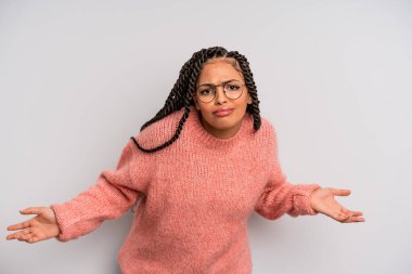 black afro woman feeling clueless and confused, having no idea, absolutely puzzled with a dumb or foolish look