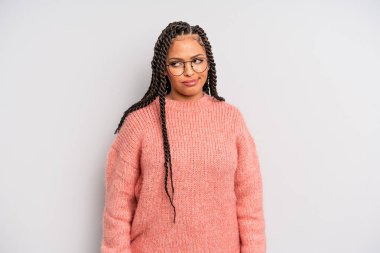 Siyah afro kadın şaşkın ve şaşkın görünüyor, merak ediyor ya da bir sorunu çözmeye çalışıyor ya da düşünüyor