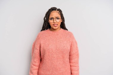 Siyah afro kadın şaşkın ve şaşkın görünüyor, gergin bir hareketle dudağını ısırıyor, sorunun cevabını bilmiyor.