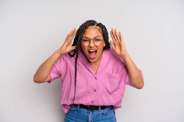 Siyah afro kadın panik ya da öfke içinde bağırıyor, şok olmuş, korkmuş ya da öfkeli, elleri başının yanında.