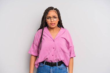 Siyah afro kadın kendini cahil, kafası karışık ve hangi seçeneği seçeceği konusunda kararsız hissediyor, sorunu çözmeye çalışıyor.