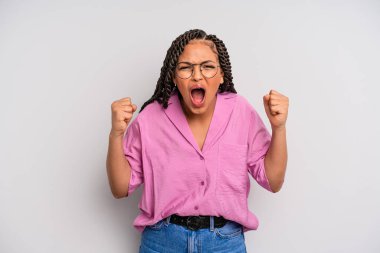 Siyah afro kadın öfkeli bir ifadeyle bağırıyor ya da yumruklarıyla başarıyı kutluyor.