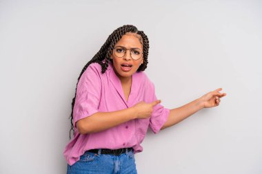 Siyah afro kadın şaşkın ve şaşırmış hissediyor, fotokopi alanını işaret ediyor, şaşkın, açık ağızlı bir bakışla