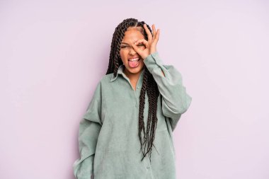 Siyah afro kadın mutlu bir şekilde gülümsüyor, şaka yapıyor ve gözetleme deliğinden bakıyor, sırları gözetliyor.