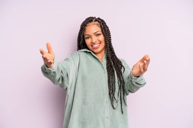 Siyah afro kadın neşeyle gülümsüyor sıcak, dostça, sevgi dolu bir kucaklama veriyor, mutlu ve sevimli hissediyor.