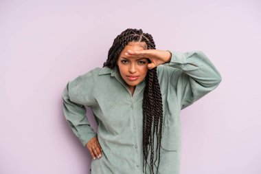 Siyah afro kadın şaşkınlık ve şaşkınlık içinde bakıyor, el üstünde uzak bakıyor, izliyor ya da arıyor