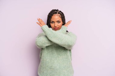 Siyah afro kadın senin bu tavırlarından rahatsız ve bıkkın görünüyor, yeter artık! Eller önde çapraz, durmanı söylüyor.